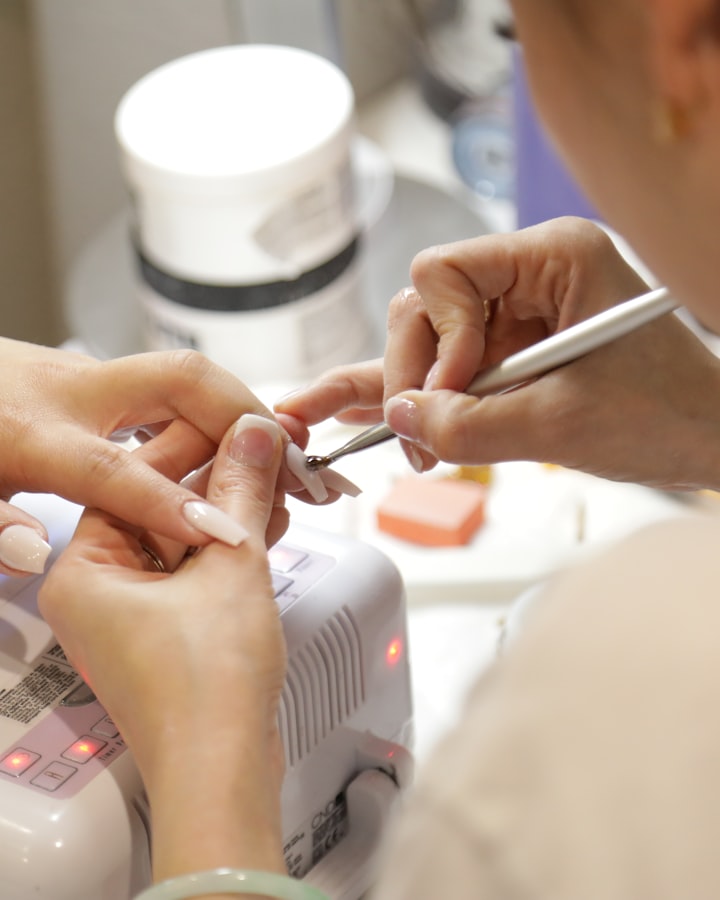 Técnica de uñas aplicando con cuidado esmalte semipermanente en la mano de una clienta